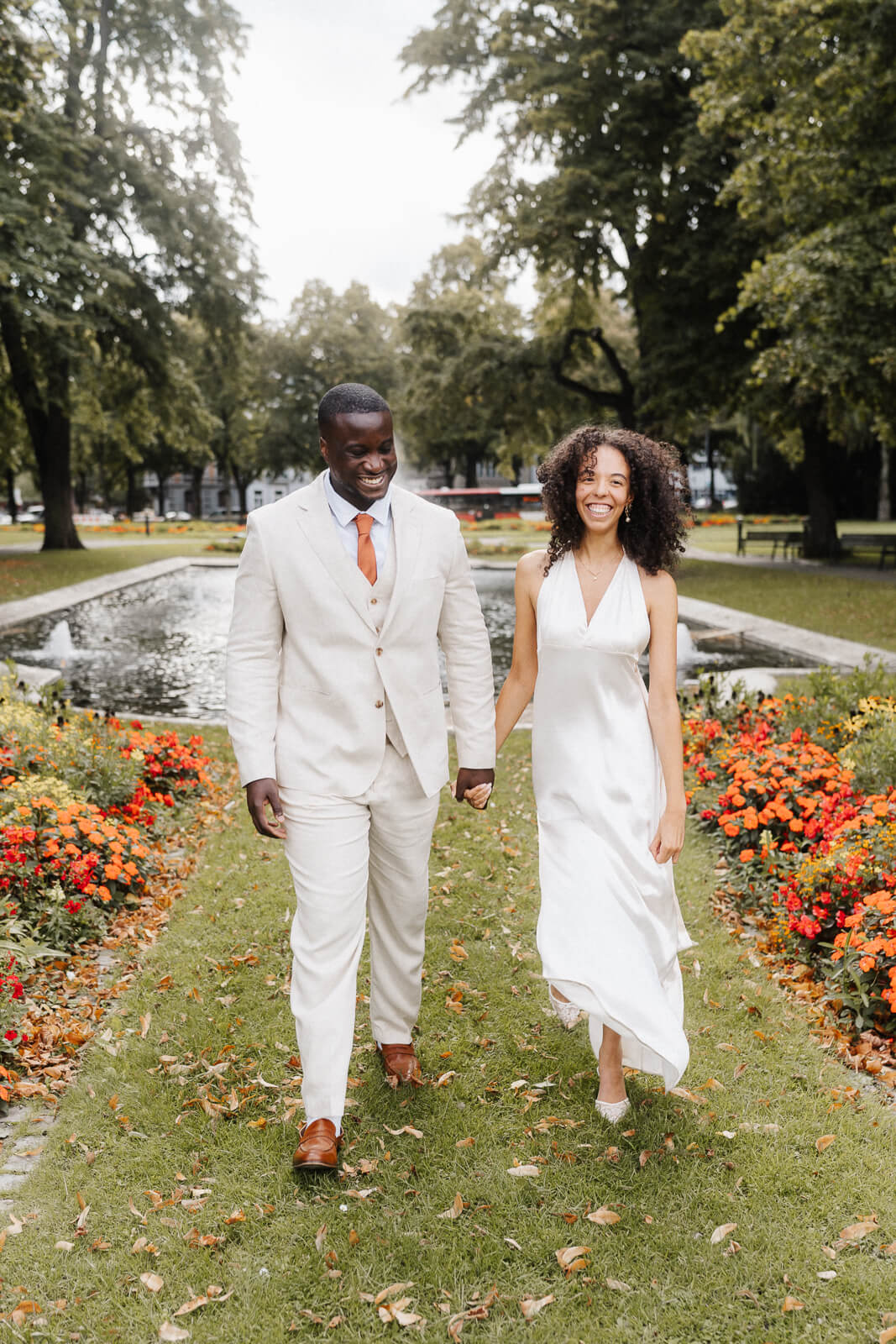 Brautpaar läuft Hand in Hand durch blühenden Garten bei Hochzeitsshooting im Sommer.